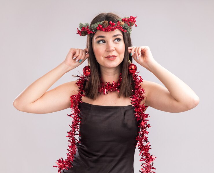 Foto grátis feliz, jovem, bonita, caucasiana, vestindo, natal, cabeça, grinalda e, ouropel, guirlanda, penduradas, natal, bugigangas, orelhas, olhando para, lado, isolado, branco, fundo