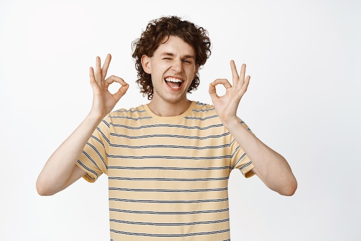 Foto grátis feliz jovem bonito mostrando sinal de ok rindo e acenando em aprovação sobre fundo branco