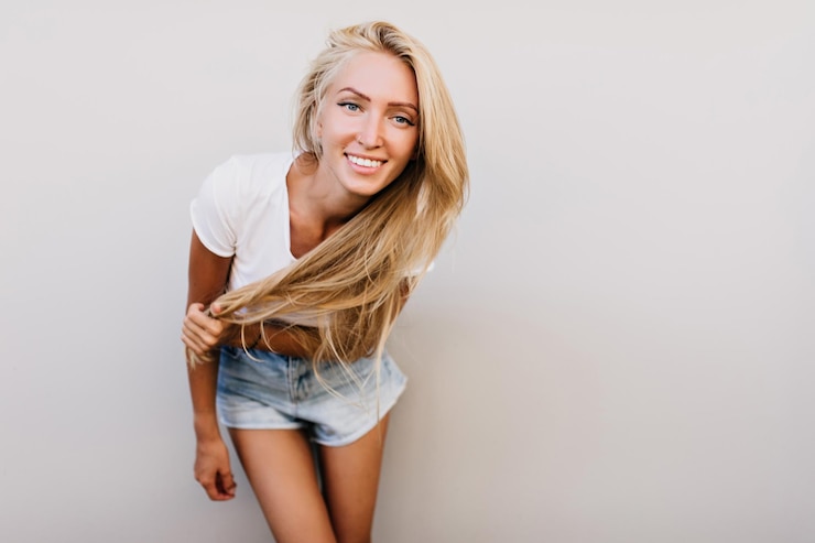 Foto grátis feliz jovem bronzeada se divertindo no estúdio modelo caucasiano espetacular com corpo bronzeado sorrindo para a câmera