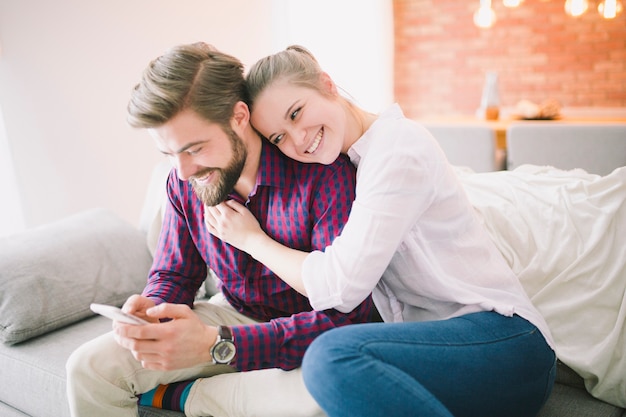 Feliz jovem casal com telefone no sofá