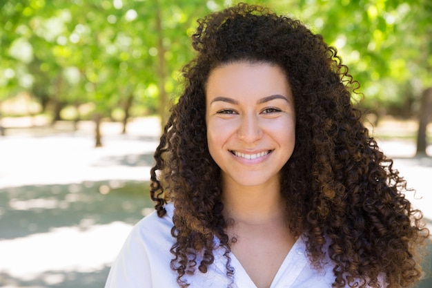 Foto grátis feliz, jovem, curly-haired, senhora, posar, câmera, parque