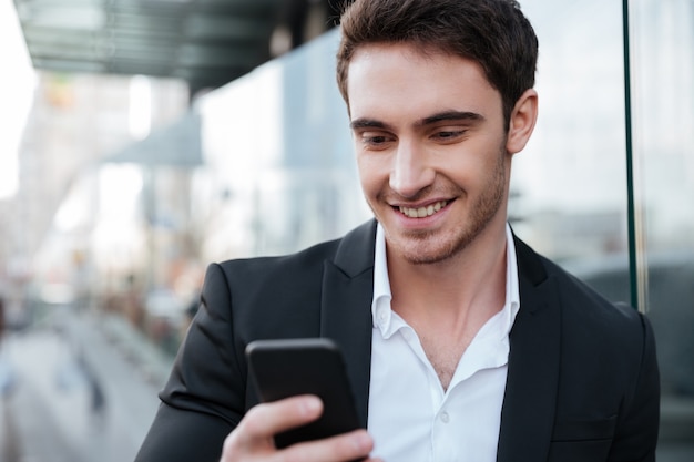 Feliz jovem empresário andando perto do centro de negócios conversando