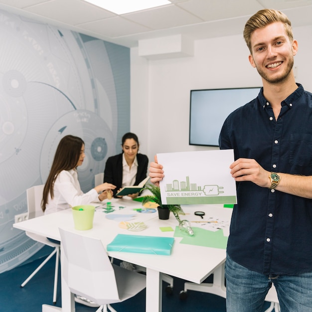 Feliz jovem empresário mostrando o conceito de economia de energia no papel