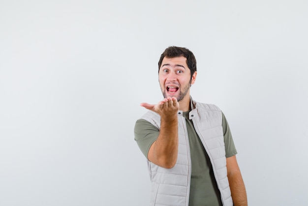 Foto grátis feliz jovem esticando a mão esquerda no fundo branco