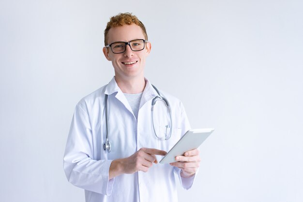 Feliz jovem médico masculino usando computador tablet