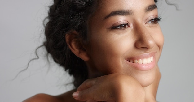 Feliz jovem serena com linda pele verde-oliva e cabelo encaracolado pele ideal e olhos castanhos no estúdio