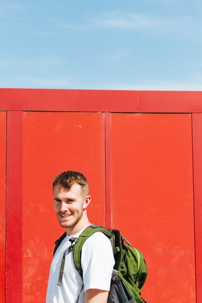 Foto grátis feliz jovem viajante masculino com mochila de viagem, olhando para a câmera