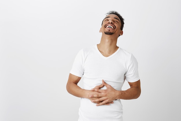 Foto grátis feliz lindo afro-americano rindo, rindo e tocando a barriga