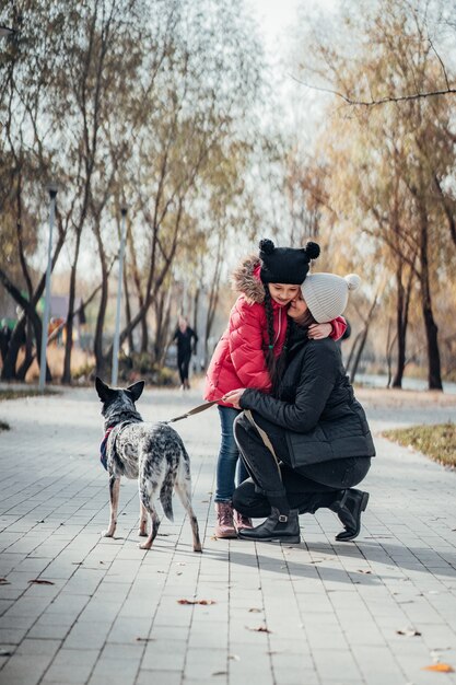 Feliz mãe e filha passear com cachorro no parque outono