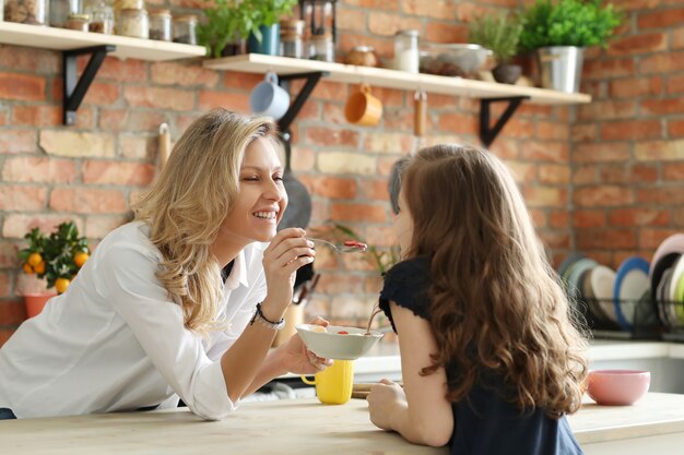 Feliz mãe e filha tomando café na cozinha