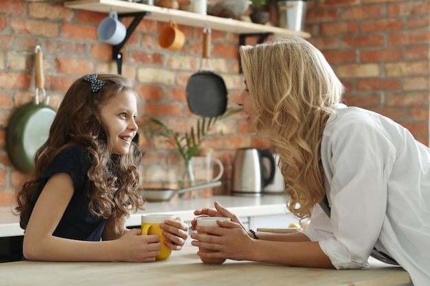 Feliz mãe e filha tomando café na cozinha