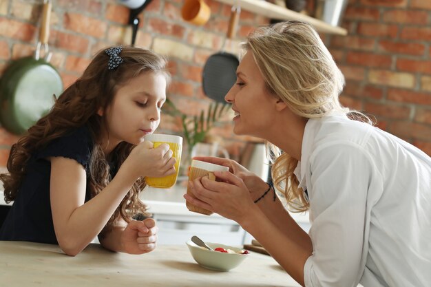 Feliz mãe e filha tomando café na cozinha