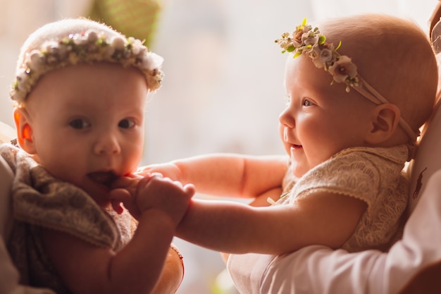 Feliz mãe e pai posam com gêmeos engraçados em seus braços antes de uma janela brilhante