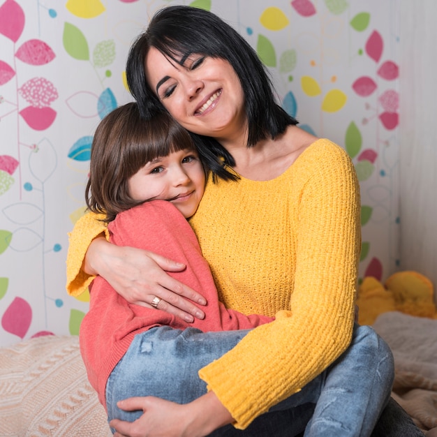 Feliz mãe filha abraça na cama