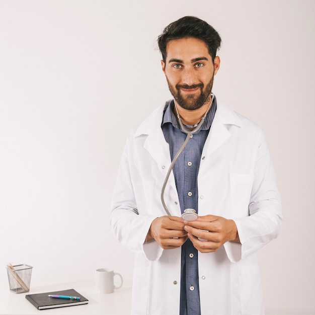 Foto grátis feliz médico posando em seu escritório