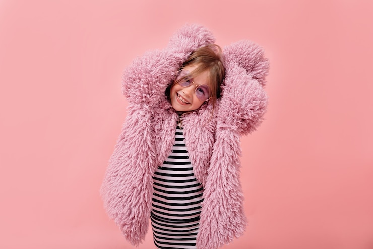 Foto grátis feliz menina adorável vestindo um casaco de pele violeta elegante e óculos redondos de moda posando