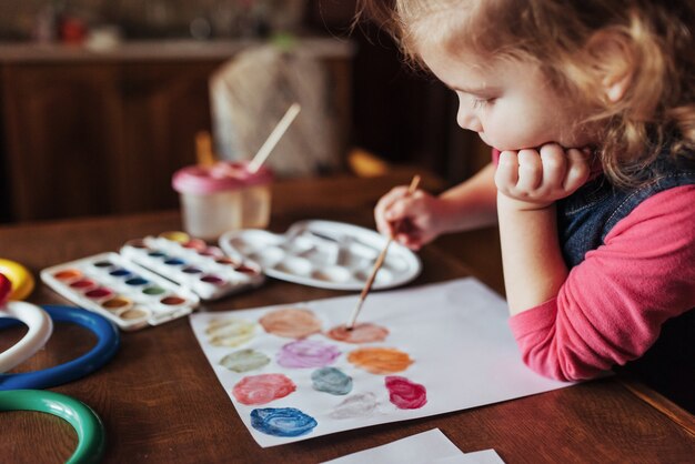 Feliz menina bonitinha, adorável criança em idade pré-escolar, pintando com wate