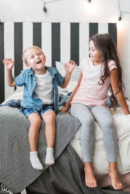 Foto grátis feliz, menina, olhar, menino sentando, cama, fazendo, travessura