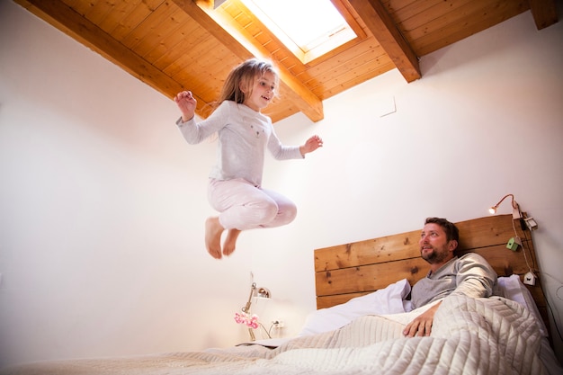 Foto grátis feliz menina pulando na cama