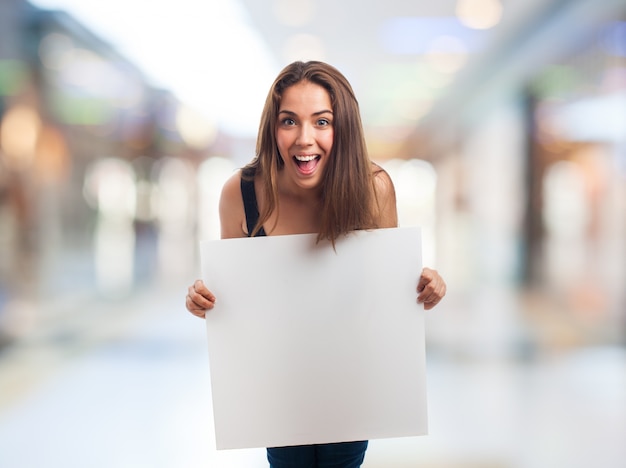 Feliz menina segurando um cartaz em branco