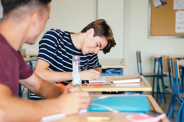 Feliz menino escrevendo na aula