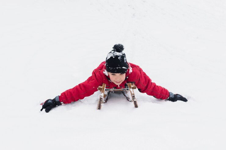 Foto grátis feliz, menino, sledging, ligado, trenó, baixo, em, nevado, paisagem