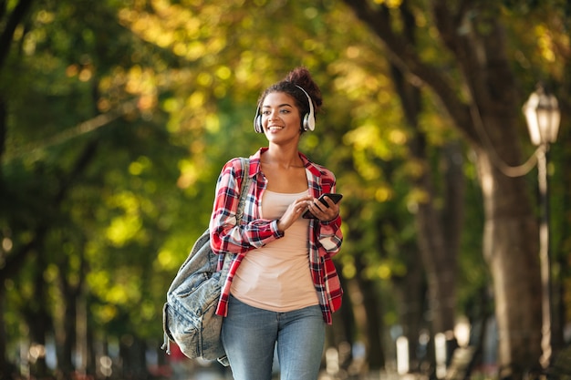 Foto grátis feliz mulher africana jovem caminhando ao ar livre no parque