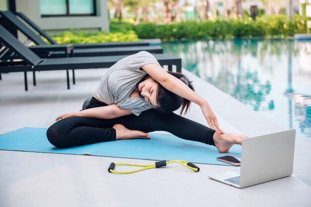 Feliz mulher asiática esticando exercícios e exercícios de ioga pela manhã em casa ao ar livre