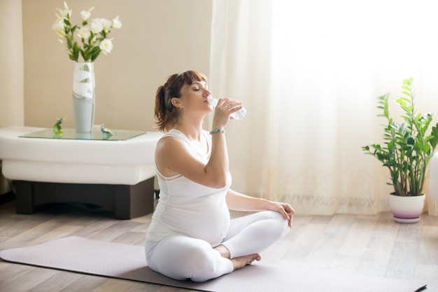 Feliz mulher grávida bebendo água natural depois de trabalhar