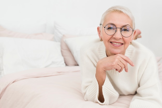 Foto grátis feliz mulher idosa posando na cama com espaço de cópia