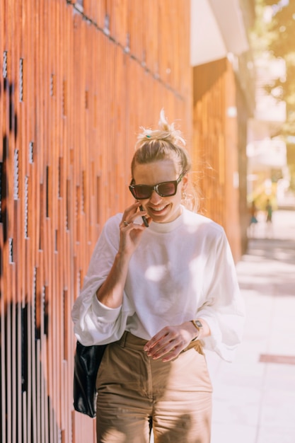 Foto grátis feliz, mulher jovem, ficar, rua, falando telefone móvel