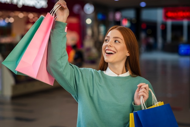 Feliz mulher levantando sacolas de compras