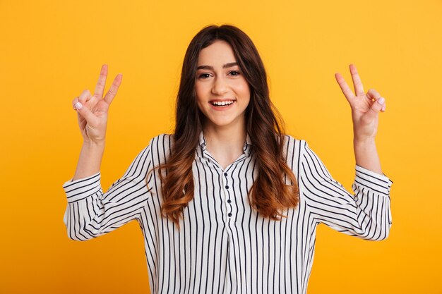 Feliz mulher morena de camisa mostrando gestos de paz