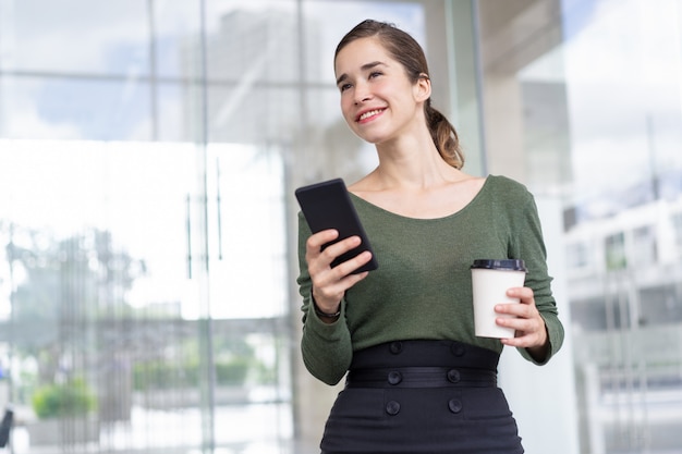 Feliz, mulher negócios fica, com, telefone móvel, e, café