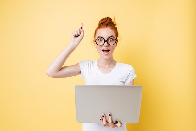 Feliz mulher ruiva de óculos, segurando o computador portátil