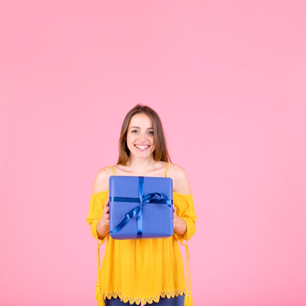 Foto grátis feliz, mulher segura, segurando, presente embrulhado, contra, fundo cor-de-rosa