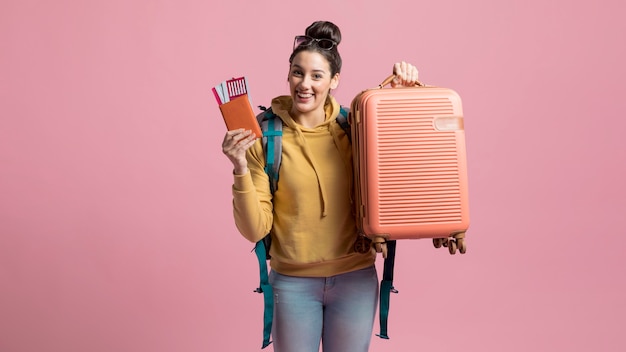 Feliz mulher segurando sua bagagem e passagem de avião