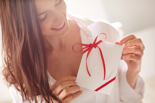 Feliz mulher segurando uma carta com um laço vermelho