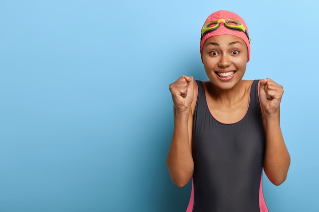 Foto grátis feliz nadador de pele escura e saudável cerrando os punhos, fazendo gesto de triunfo
