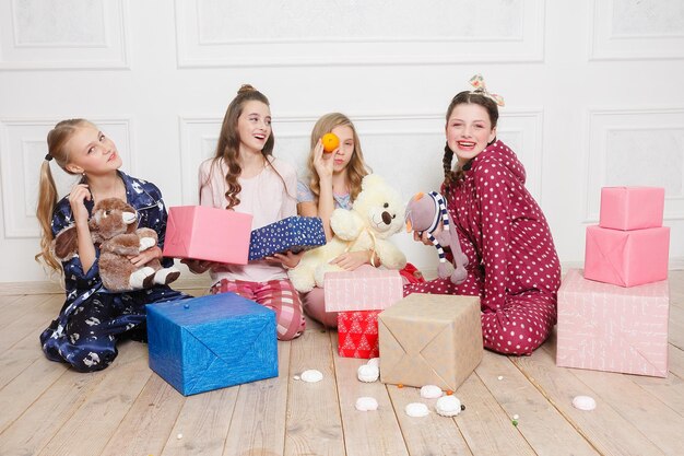 Feliz natal e feliz ano novo linda menina feliz quatro crianças de pijama esperando um milagre em casa com a árvore de natal. menina sorridente com caixa de presente de natal. férias, conceito de pessoas.