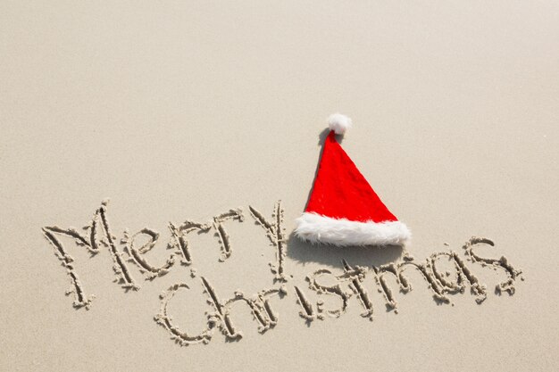 Feliz Natal escrito na areia com o chapéu de Santa