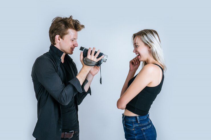 Foto grátis feliz, retrato, de, par, segurando, câmera video, e, registro, clipe, vídeo