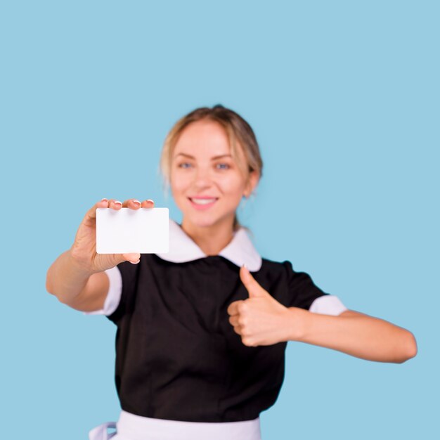 Feliz zelador muito feminino, mostrando o cartão de visita em branco e o polegar para cima gesto