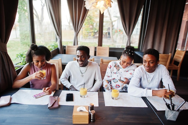 Felizes amigos africanos sentados e conversando no café grupo de negros se encontrando e bebendo suco no restaurante