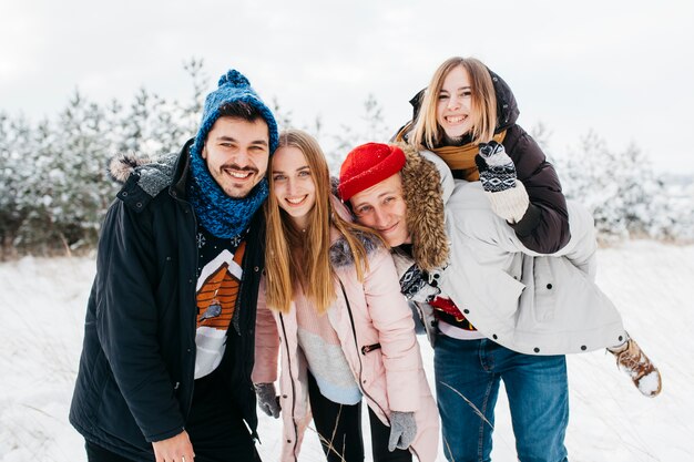 Felizes amigos em pé na floresta de inverno