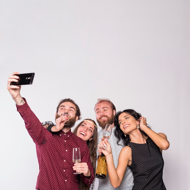 Felizes amigos fazendo selfie com champanhe