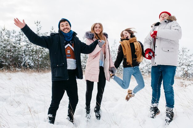 Felizes amigos pulando na floresta de inverno