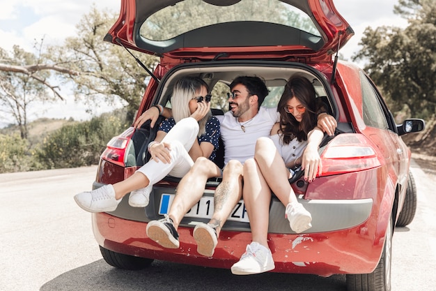 Felizes amigos tirando sarro na mala do carro na estrada