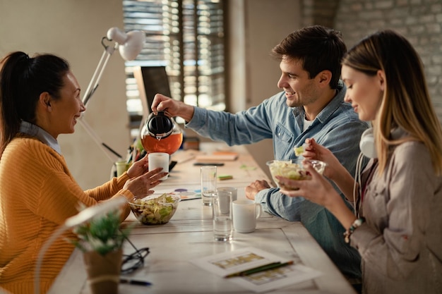 Foto grátis felizes colegas criativos bebendo chá durante a pausa para o almoço no escritório