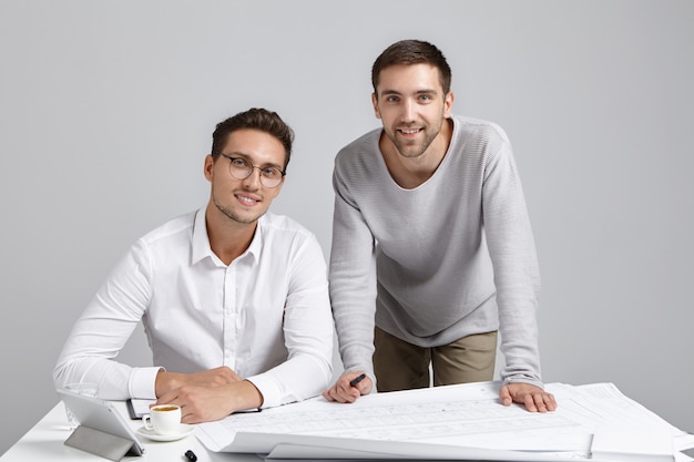 Foto grátis felizes jovens empresários ou funcionários de design sentados no local de trabalho, cercados de plantas